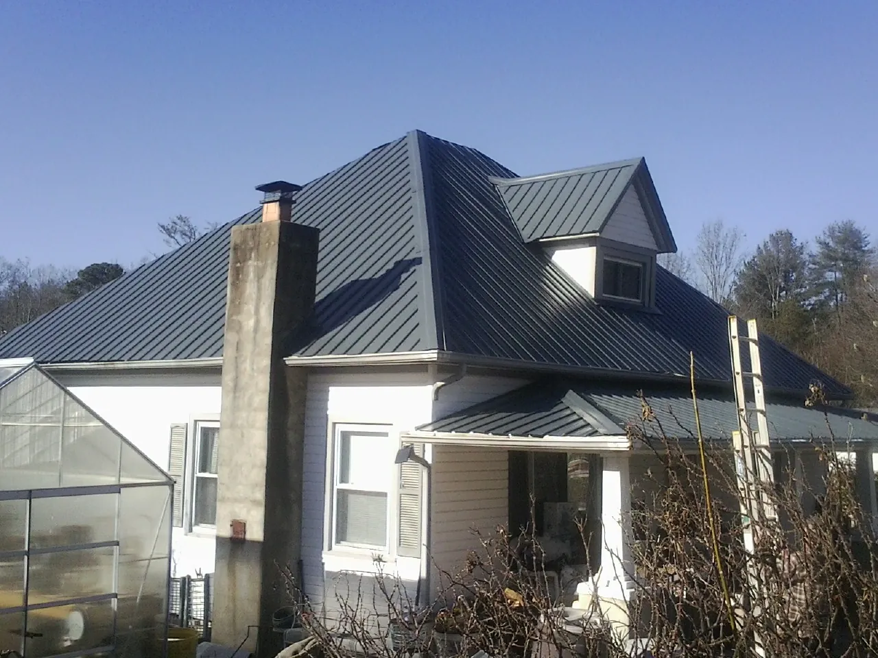 Dark blue standing seam metal roof on a white farmhouse with dormer — Slate & Tile Roof Repair by Roofing Brothers in Topping