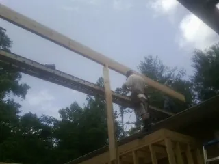 Carpenter setting a ridge beam over a new addition frame — Ice Dam Removal by Roofing Brothers in Topping