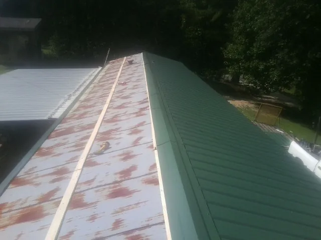 Old rusted panels beside newly installed green metal roofing — Wind Damage Roof Repair by Roofing Brothers in Topping