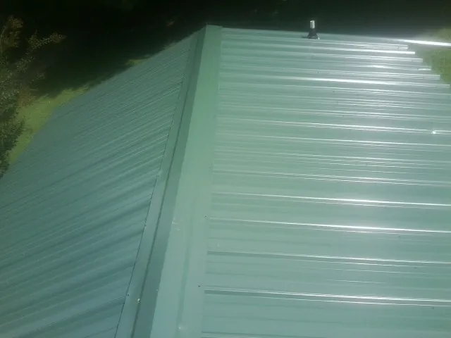 New green metal panels meeting at the ridge of a roof — Flat Roof Repair work by our crew in Topping