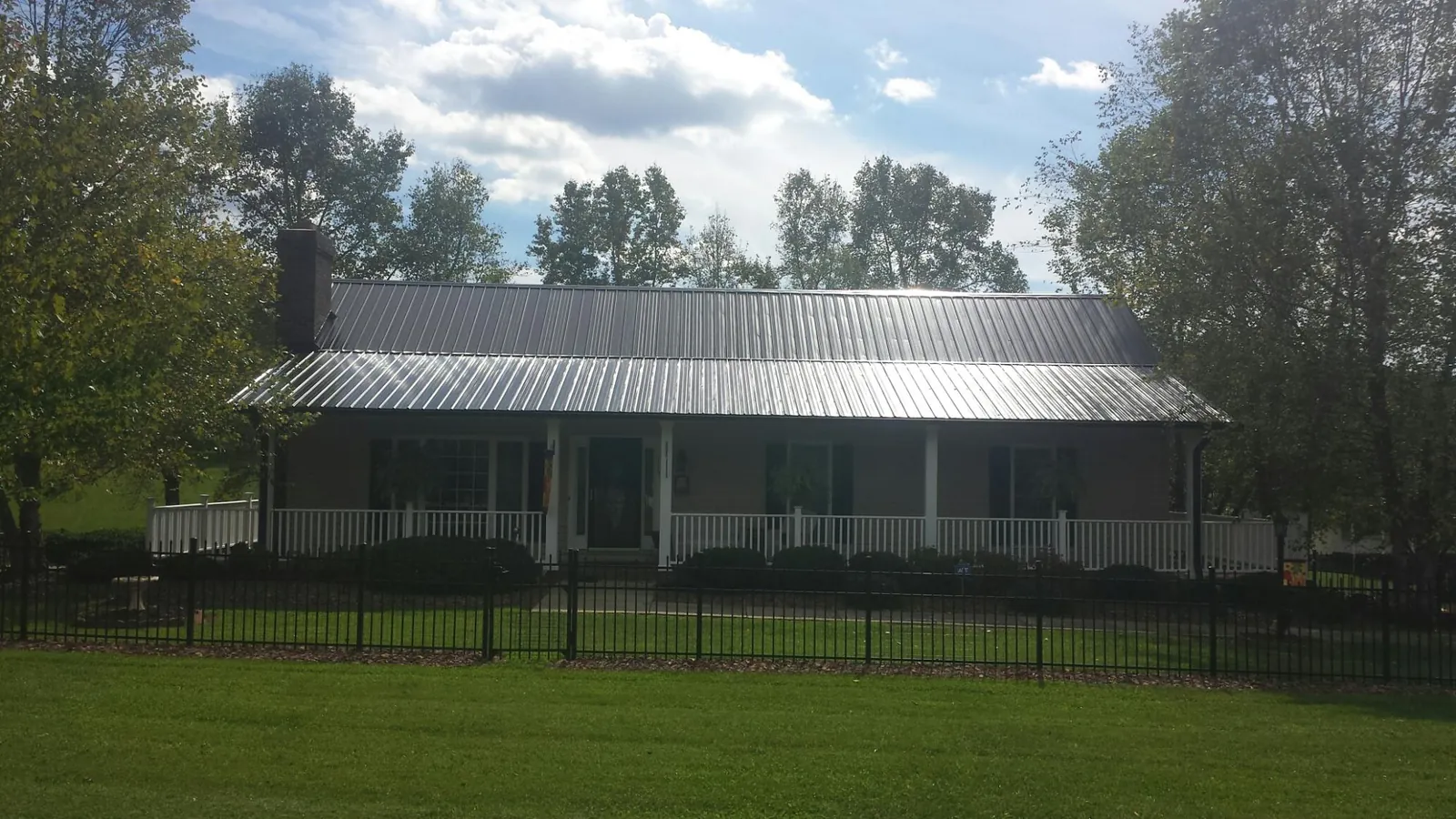 Gray metal roof on a brick ranch with a full width front porch — Gutter Guard Installation work by our crew in Topping
